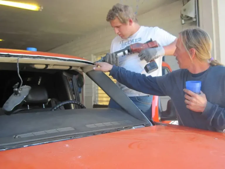 Technician instructing son while applying urethane on Chevy Silverado windshield replacement in Mesa Arizona