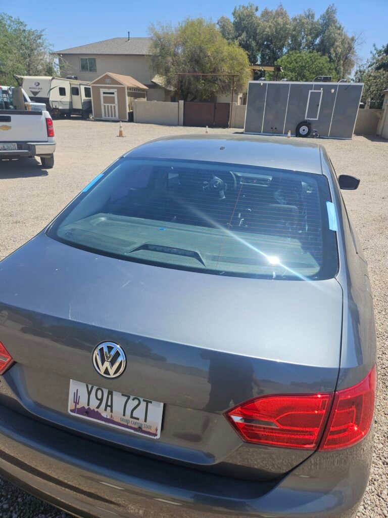 Technician replacing back glass on Volkswagen Jetta in Gilbert Arizona with professional auto glass tools