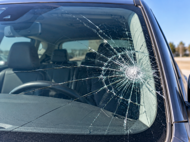 Severely cracked windshield with extensive impact damage and long cracks spreading across the glass