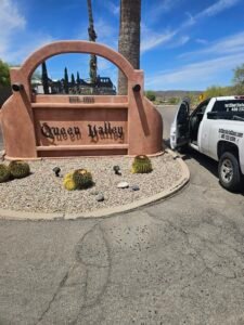 Get Up to $450 Cash Back At Queen Valley! 1 work truck at Queen Valley main entrance Arizona desert community sign and roadway