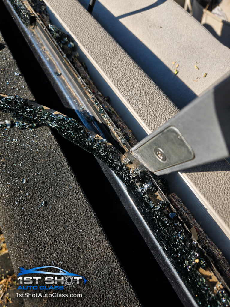 Using a pipe knife to trim the remaining adhesive and glass from a 2009 GMC Sierra back glass opening during replacement in Chandler, AZ.