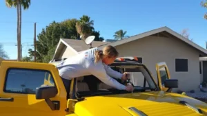 Technician trimming old urethane adhesive from the windshield frame during a Hummer H3 windshield replacement at a customer's home in Mesa, Arizona.