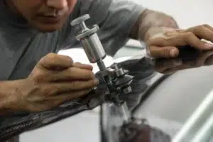 Technician repairing a windshield rock chip with a professional resin injector tool during mobile windshield repair service.