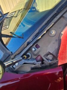 Socket tool loosening a windshield molding retainer bolt on a red 2017 Ford Explorer