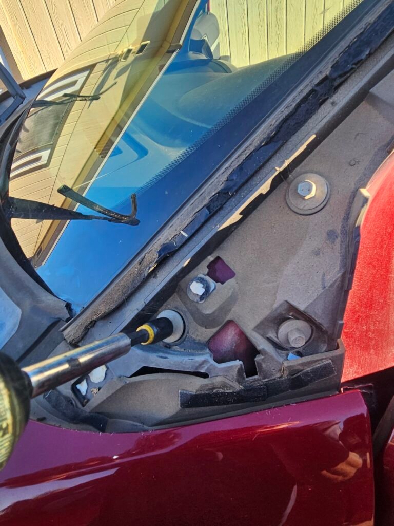 Socket tool loosening a windshield molding retainer bolt on a red 2017 Ford Explorer